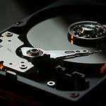 High-resolution image of computer hard drive, showcasing storage device with spinning disk and actuator arm.