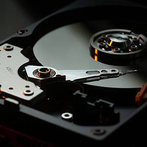 High-resolution image of computer hard drive, showcasing storage device with spinning disk and actuator arm.